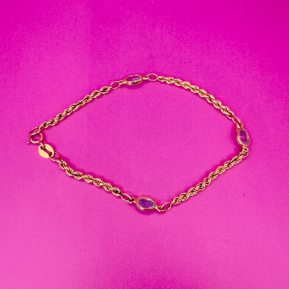 A 9ct yellow gold rope chain bracelet featuring oval bezel-set light blue topaz gemstones at spaced intervals. View VI