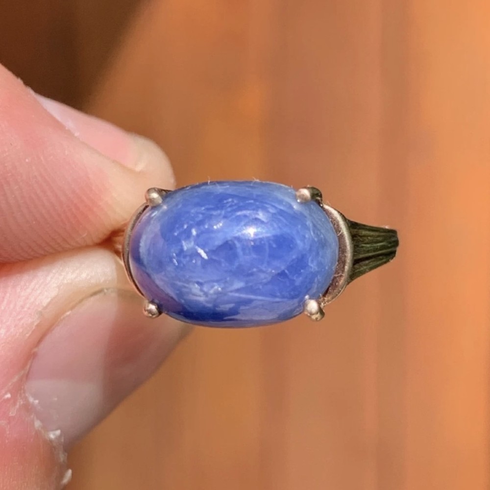A vintage 9ct yellow gold ring featuring a central oval cabochon blue sapphire set in four claws.