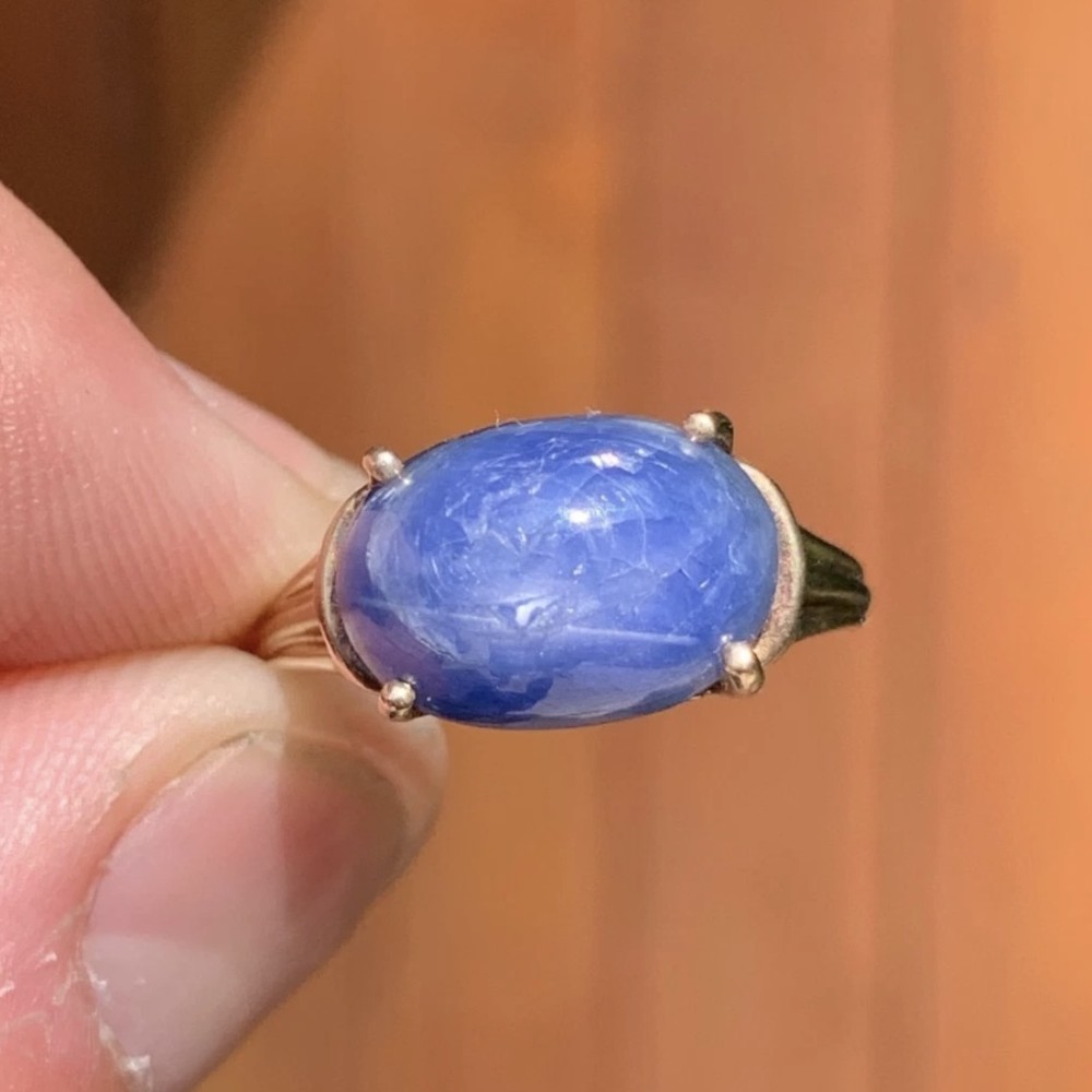 A vintage 9ct yellow gold ring featuring a central oval cabochon blue sapphire set in four claws. View III