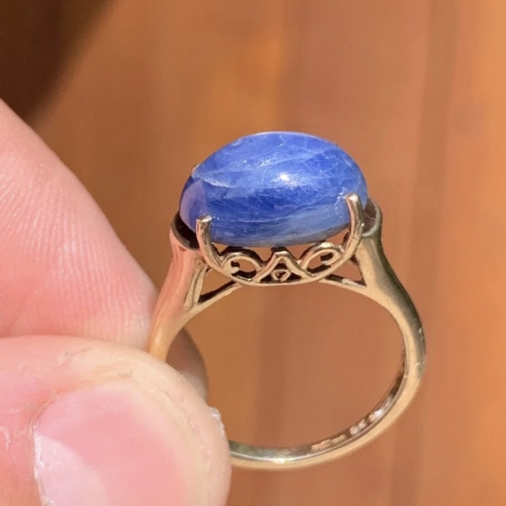 A vintage 9ct yellow gold ring featuring a central oval cabochon blue sapphire set in four claws. View IV