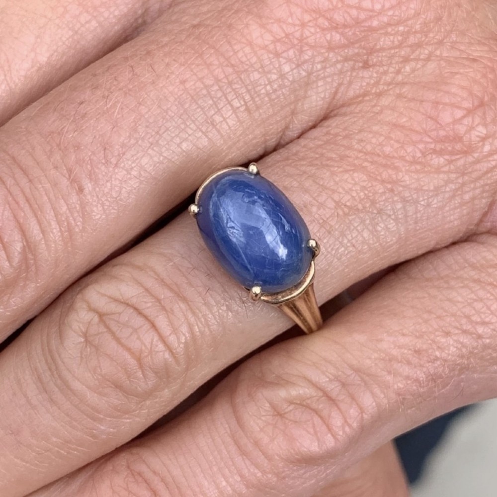 A vintage 9ct yellow gold ring featuring a central oval cabochon blue sapphire set in four claws. View V