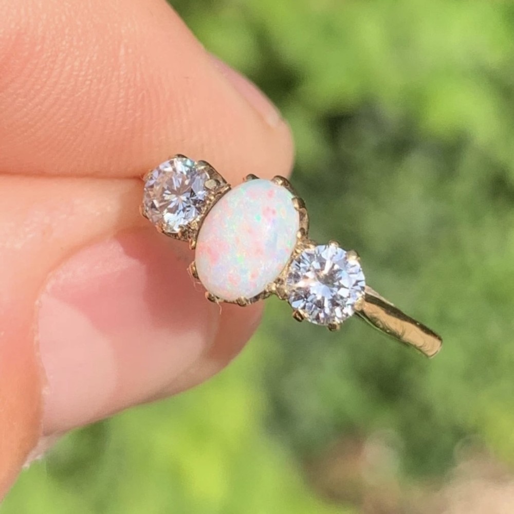 An 18ct yellow gold Art Deco ring featuring an oval cabochon opal flanked by two round diamonds in claw settings. View III