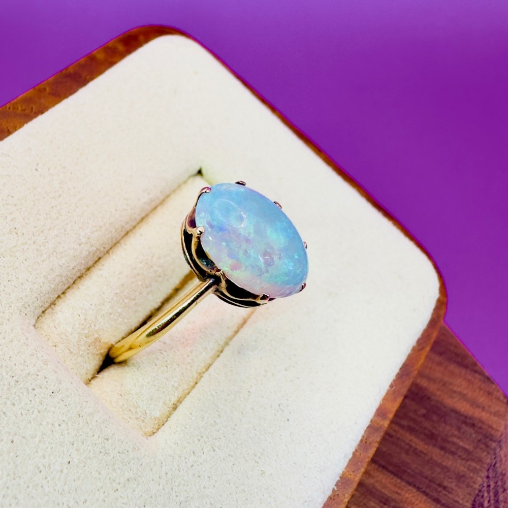 An 18ct yellow gold Victorian solitaire ring featuring an oval cabochon opal in a claw setting. View V