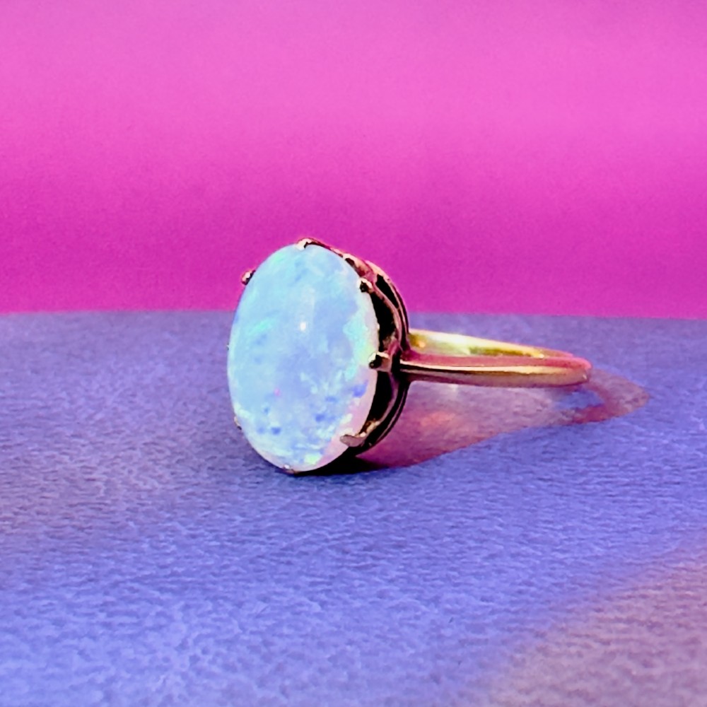 An 18ct yellow gold Victorian solitaire ring featuring an oval cabochon opal in a claw setting. View IX