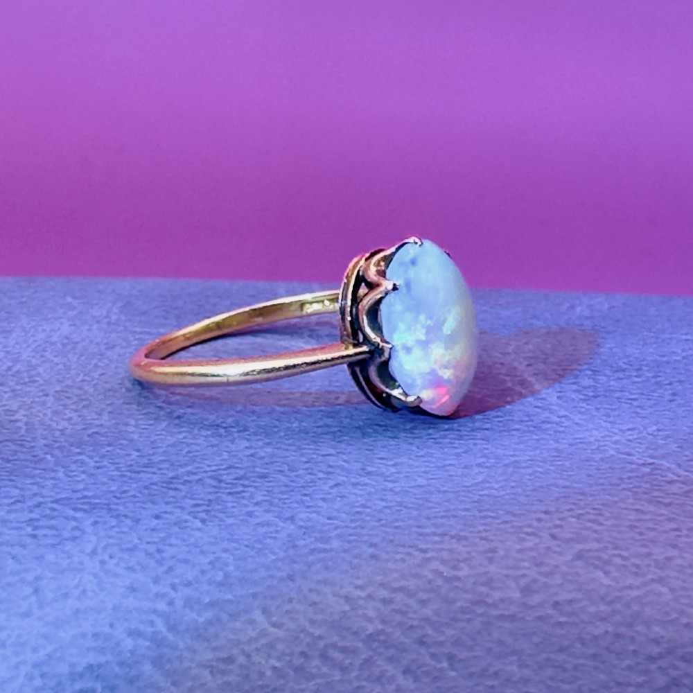 An 18ct yellow gold Victorian solitaire ring featuring an oval cabochon opal in a claw setting. View XI