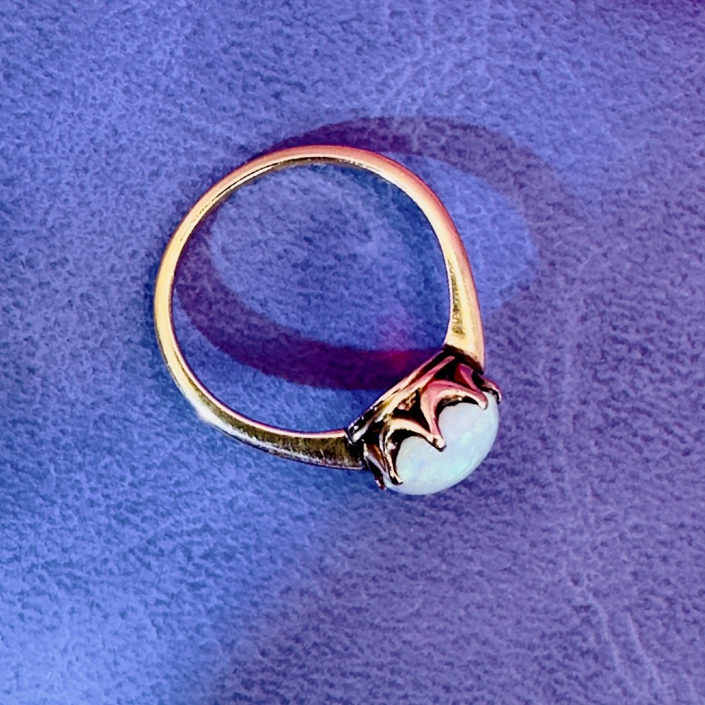 An 18ct yellow gold Victorian solitaire ring featuring an oval cabochon opal in a claw setting. View XII