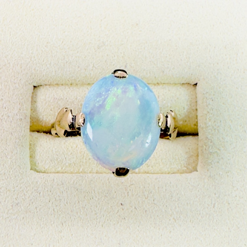 An antique 9ct yellow gold ring featuring a large oval cabochon opal with iridescent flashes held in a claw setting with decorative leaf shoulders. View II
