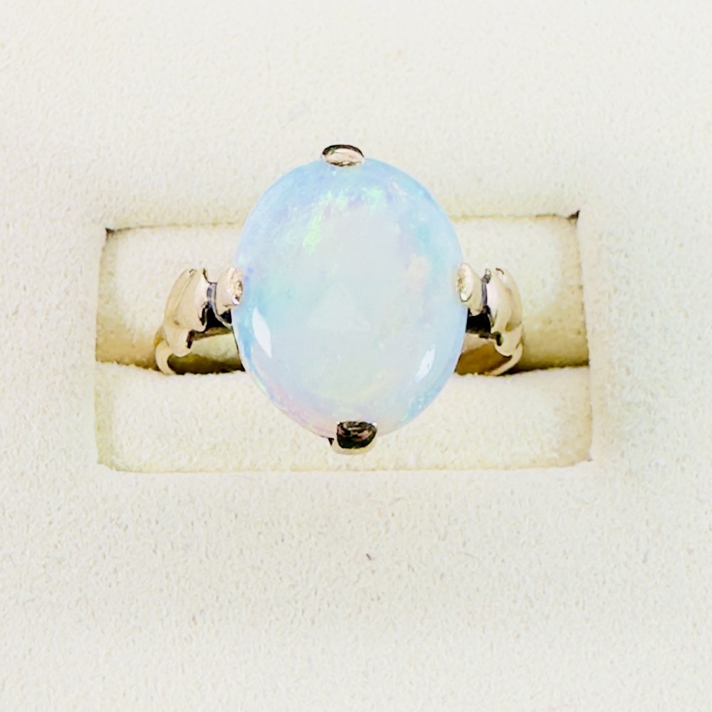 An antique 9ct yellow gold ring featuring a large oval cabochon opal with iridescent flashes held in a claw setting with decorative leaf shoulders. View IV