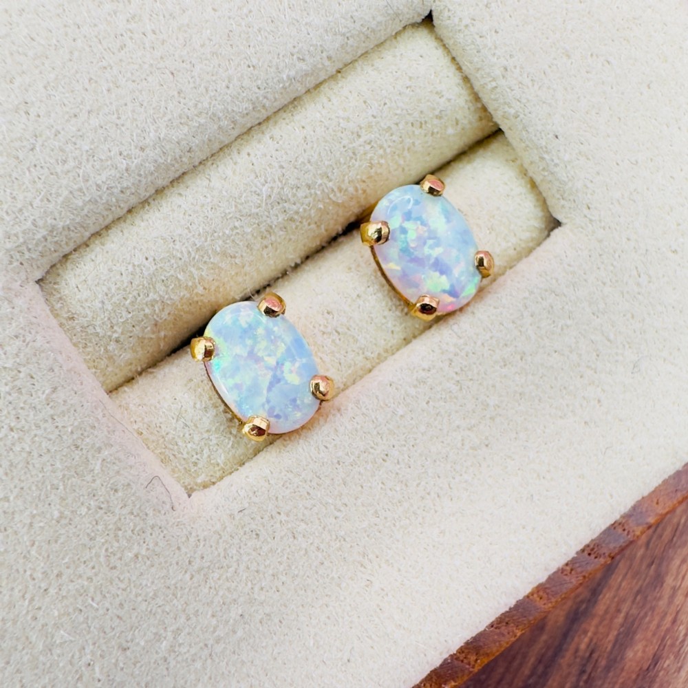 A pair of 14ct yellow gold stud earrings featuring oval-cut white opals held in four-claw settings. View V