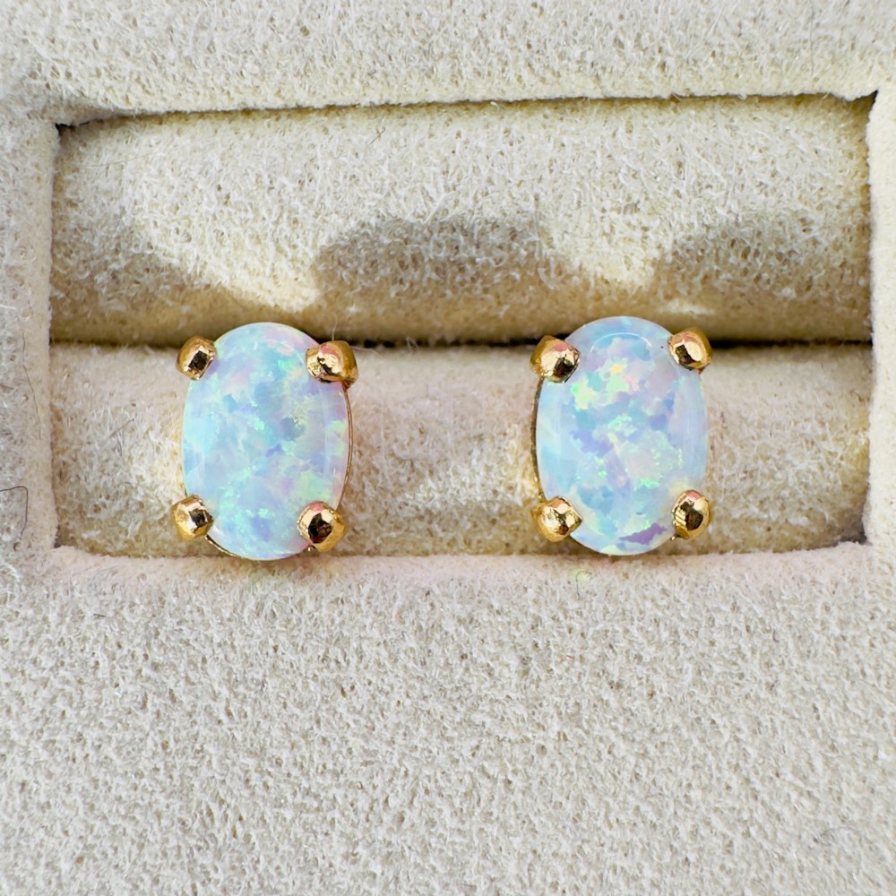 A pair of 14ct yellow gold stud earrings featuring oval-cut white opals held in four-claw settings. View VI
