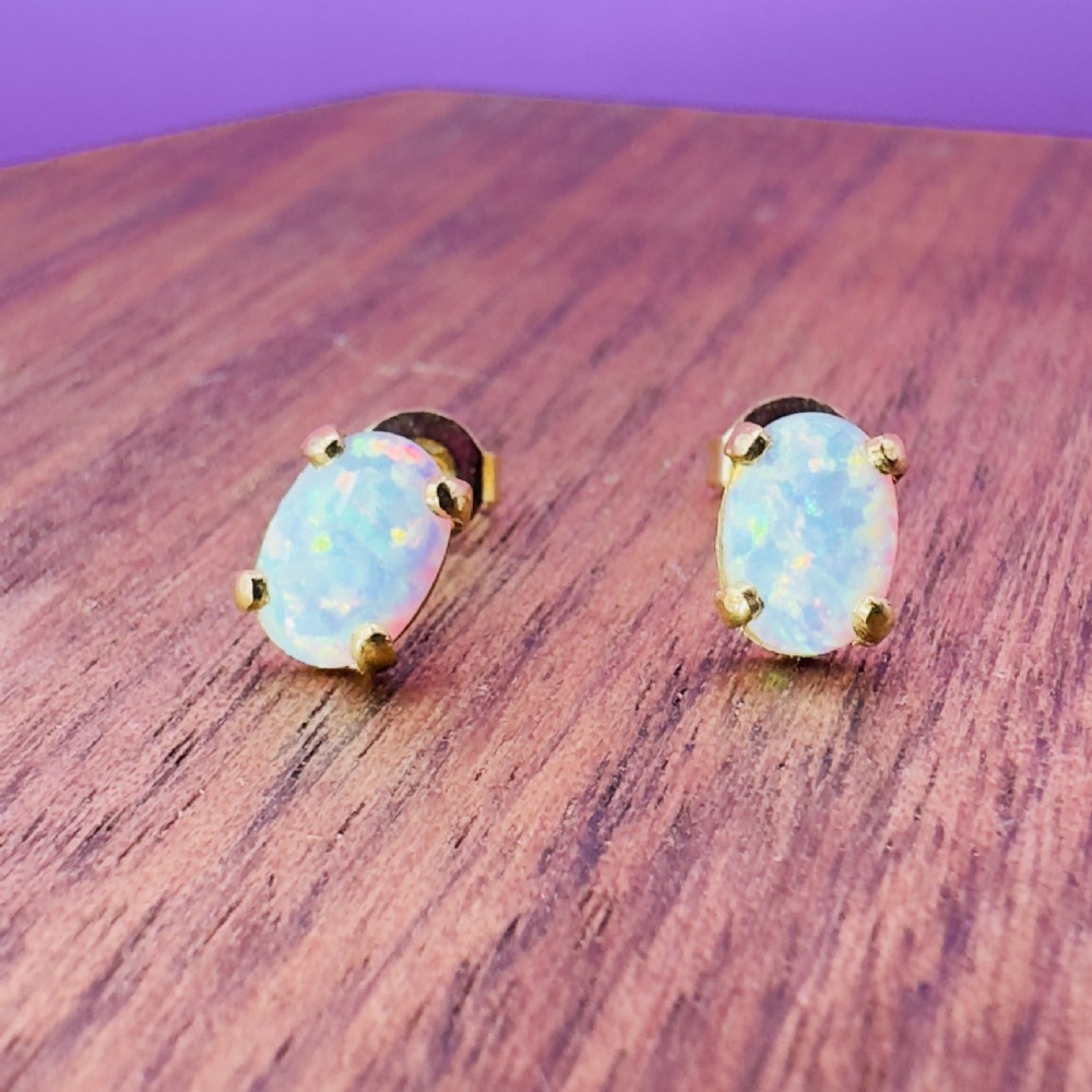 A pair of 14ct yellow gold stud earrings featuring oval-cut white opals held in four-claw settings. View VII