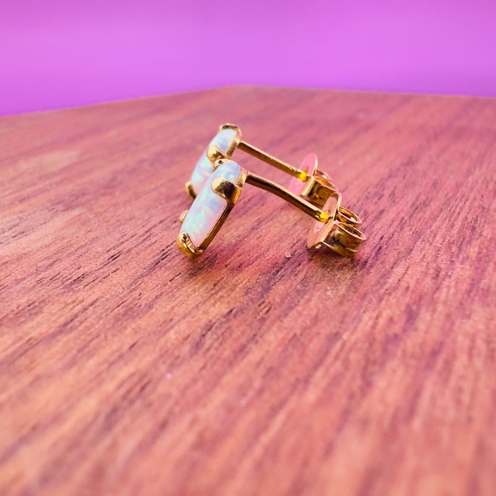 A pair of 14ct yellow gold stud earrings featuring oval-cut white opals held in four-claw settings. View VIII
