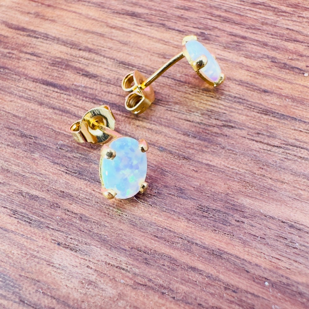 A pair of 14ct yellow gold stud earrings featuring oval-cut white opals held in four-claw settings. View IX