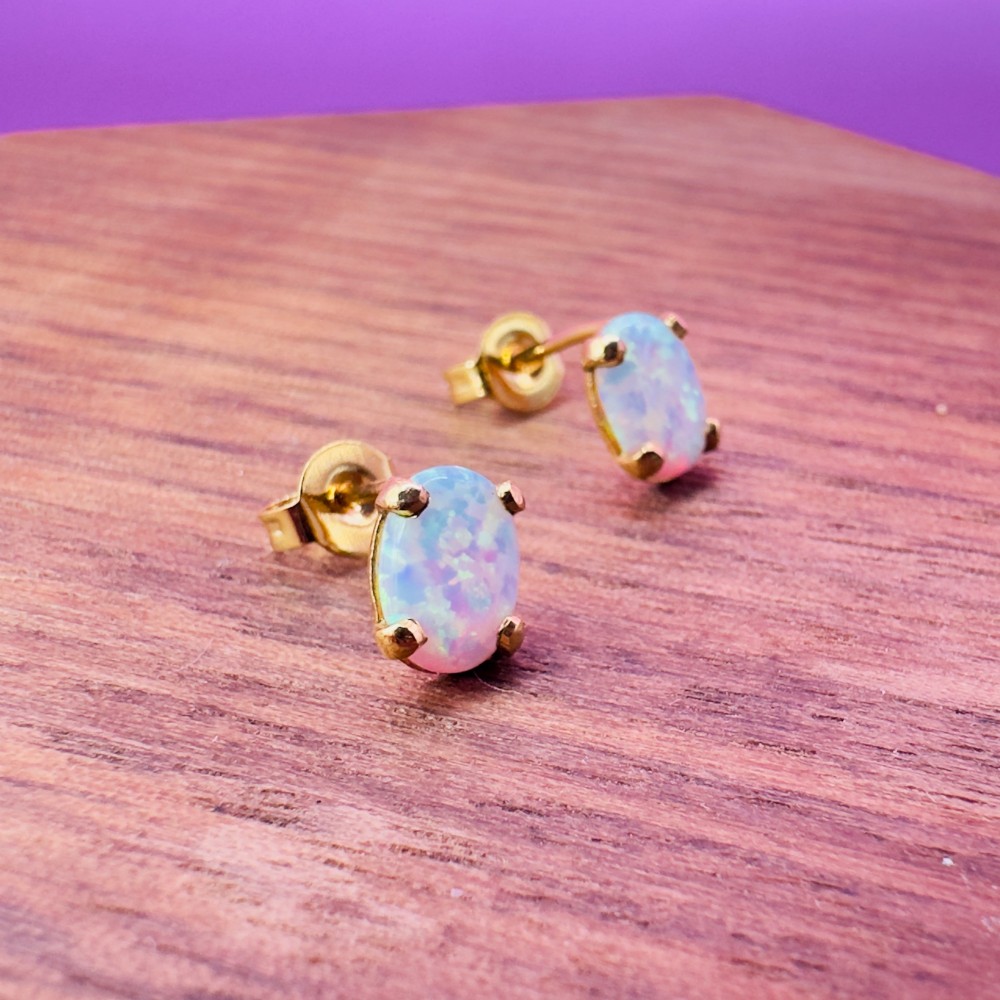 A pair of 14ct yellow gold stud earrings featuring oval-cut white opals held in four-claw settings. View X