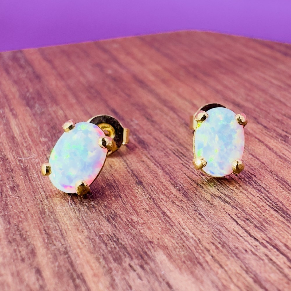 A pair of 14ct yellow gold stud earrings featuring oval-cut white opals held in four-claw settings. View XI