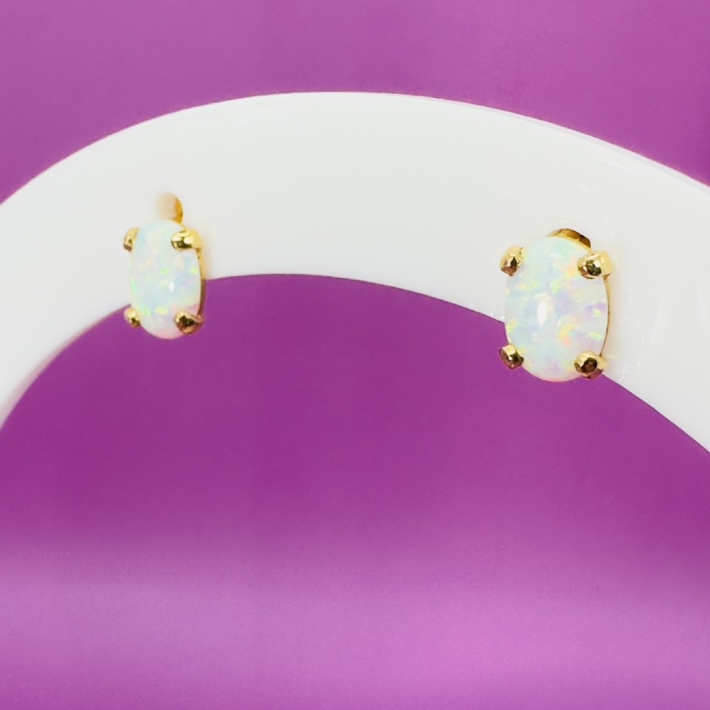 A pair of 14ct yellow gold stud earrings featuring oval-cut white opals held in four-claw settings. View XIII