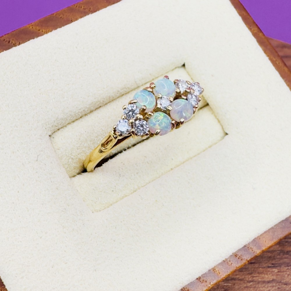 An 18ct yellow gold cluster ring set with four round cabochon opals centrally and flanked by small diamonds. View IV