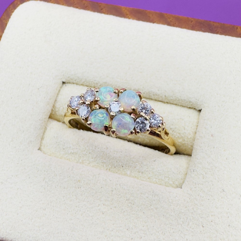 An 18ct yellow gold cluster ring set with four round cabochon opals centrally and flanked by small diamonds. View V