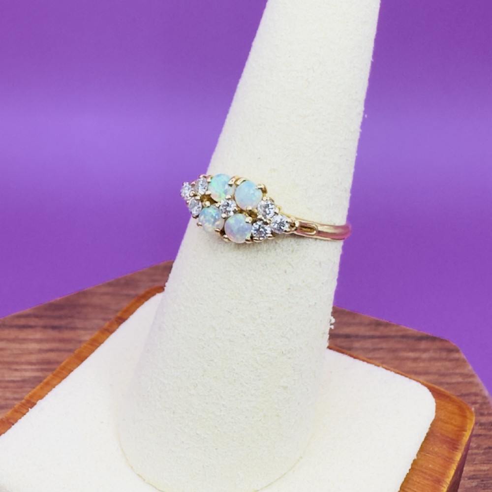 An 18ct yellow gold cluster ring set with four round cabochon opals centrally and flanked by small diamonds. View VI