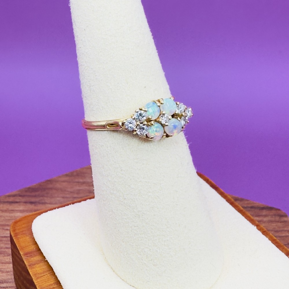 An 18ct yellow gold cluster ring set with four round cabochon opals centrally and flanked by small diamonds. View VII