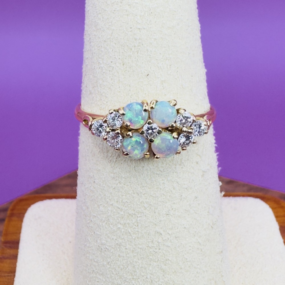 An 18ct yellow gold cluster ring set with four round cabochon opals centrally and flanked by small diamonds. View VIII