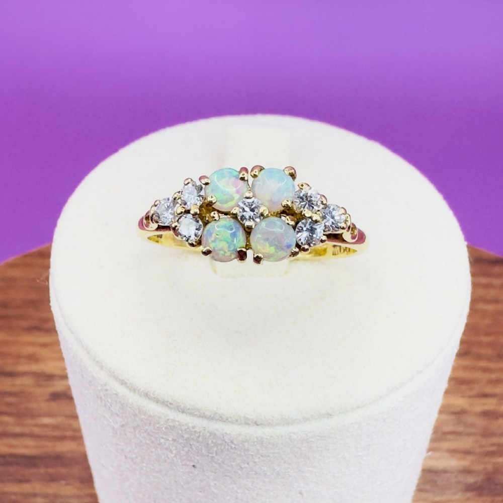 An 18ct yellow gold cluster ring set with four round cabochon opals centrally and flanked by small diamonds. View IX