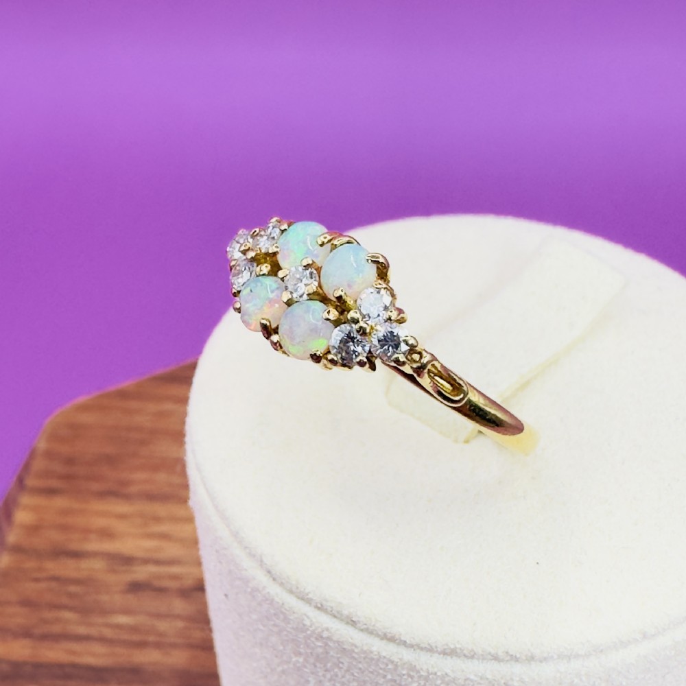 An 18ct yellow gold cluster ring set with four round cabochon opals centrally and flanked by small diamonds. View X
