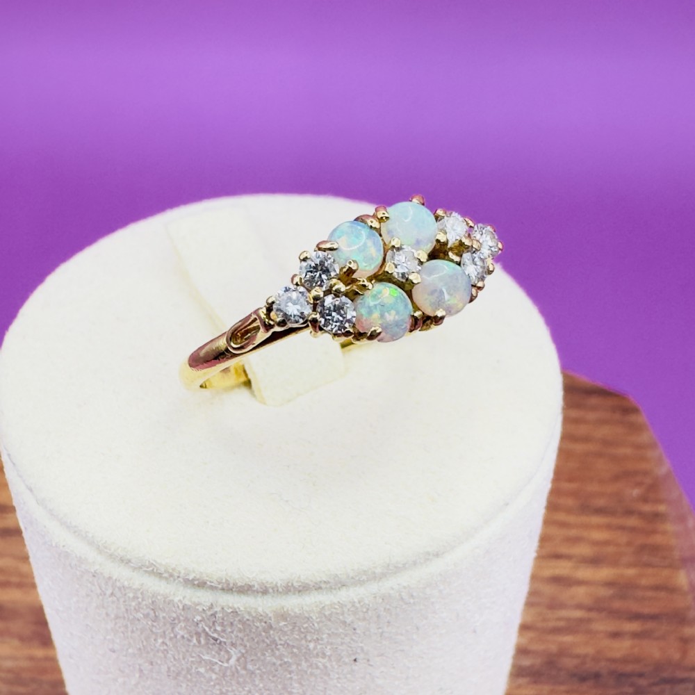 An 18ct yellow gold cluster ring set with four round cabochon opals centrally and flanked by small diamonds. View XI