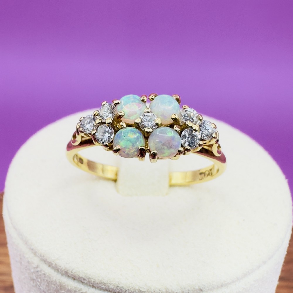 An 18ct yellow gold cluster ring set with four round cabochon opals centrally and flanked by small diamonds. View XII