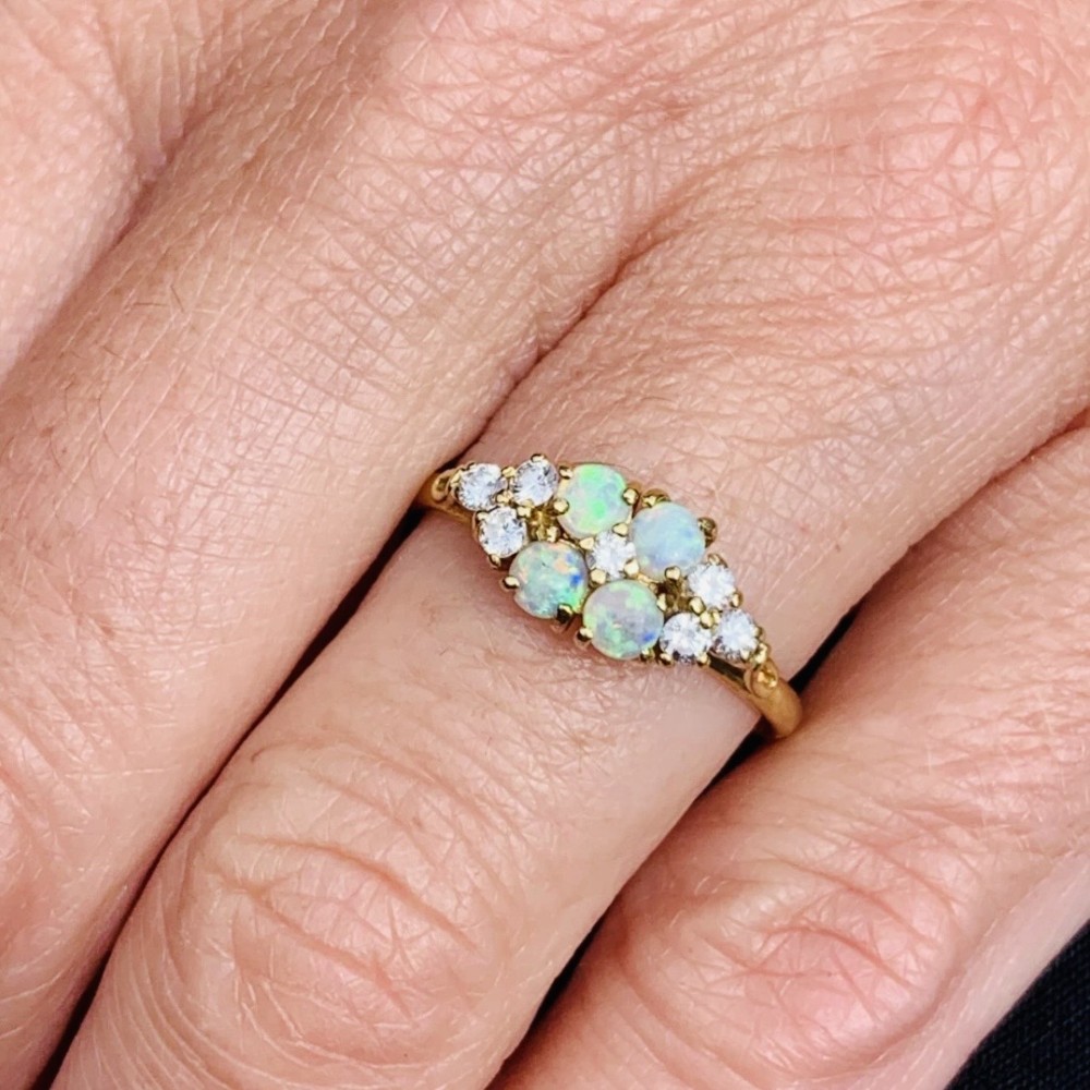 An 18ct yellow gold cluster ring set with four round cabochon opals centrally and flanked by small diamonds. View XIII
