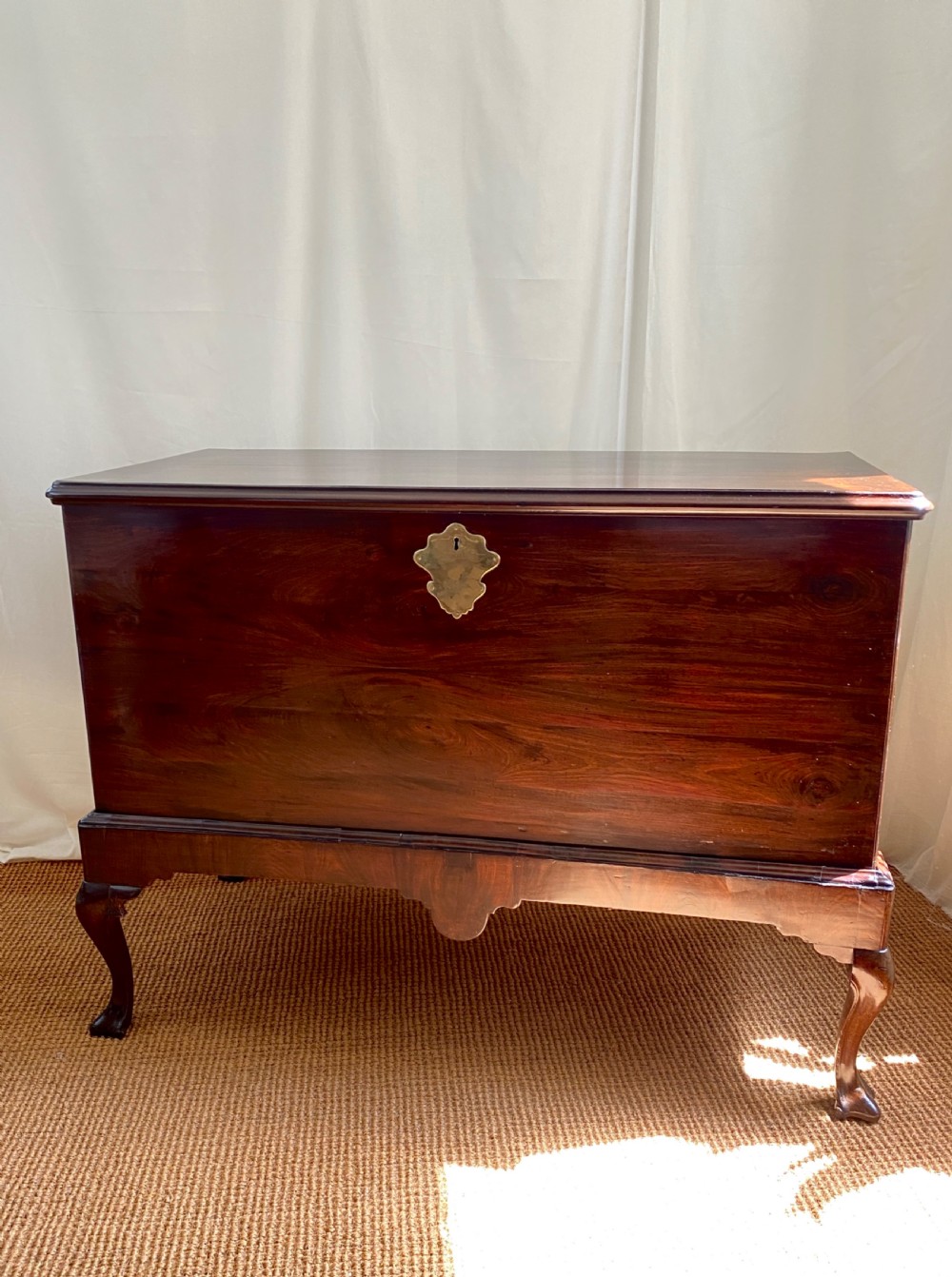 An Irish George III mahogany chest on a stand featuring a brass escutcheon, shaped apron, and carved cabriole legs.