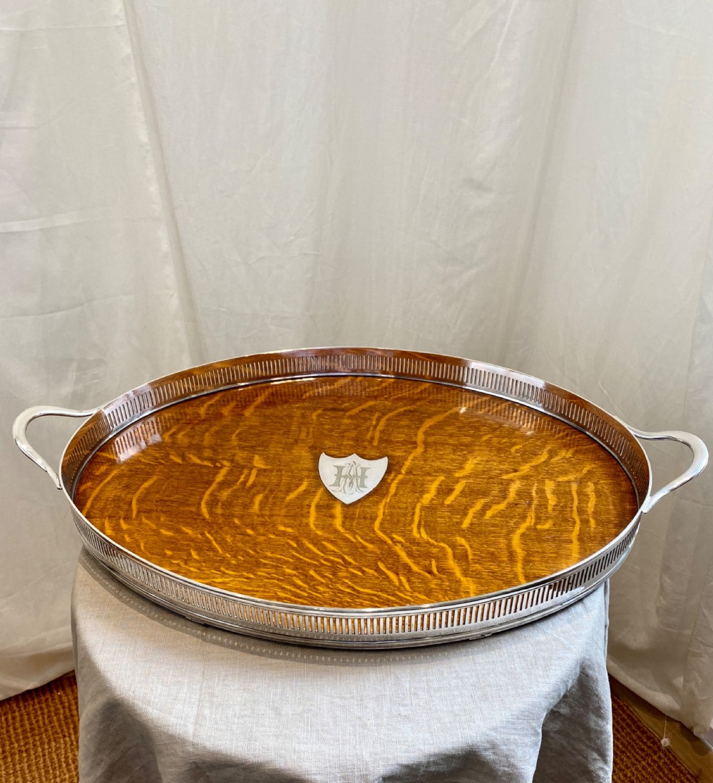 An oval 19th-century quarter-sawn oak gallery tray featuring a pierced silver-plated rim, central engraved shield plaque, and side carrying handles. View IV