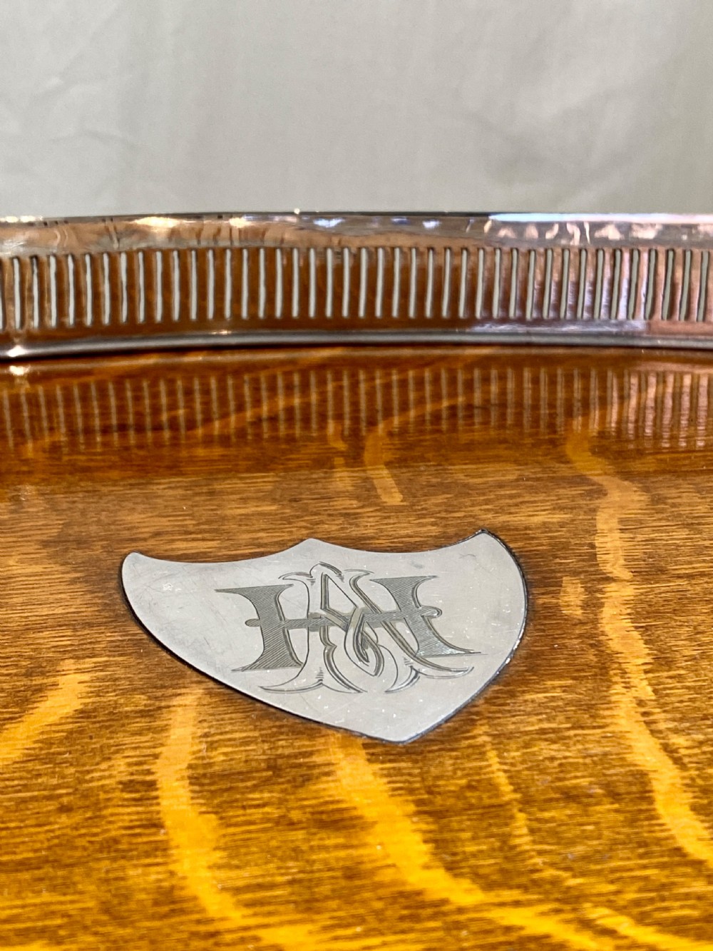 An oval 19th-century quarter-sawn oak gallery tray featuring a pierced silver-plated rim, central engraved shield plaque, and side carrying handles. View III