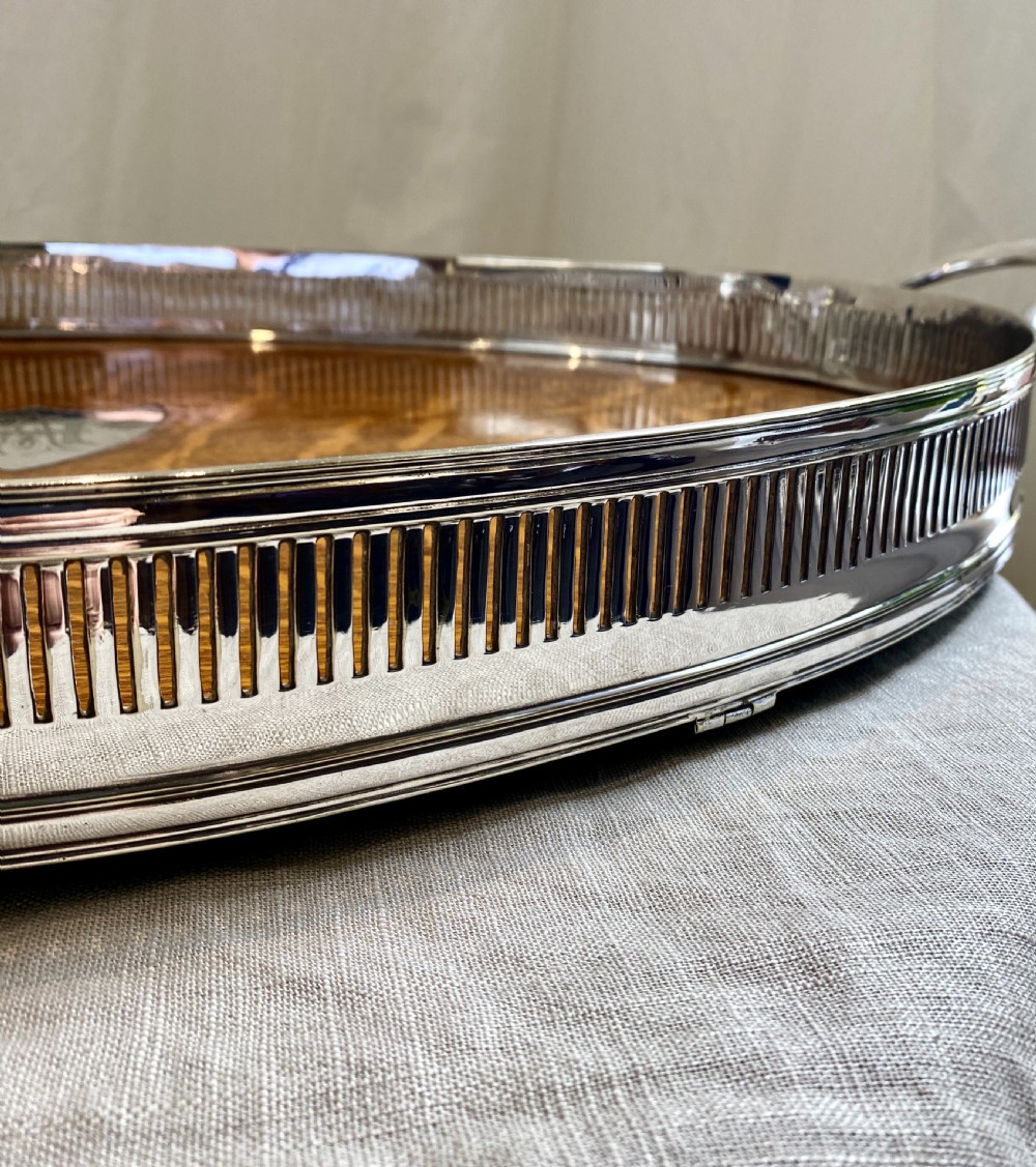 An oval 19th-century quarter-sawn oak gallery tray featuring a pierced silver-plated rim, central engraved shield plaque, and side carrying handles. View VIII
