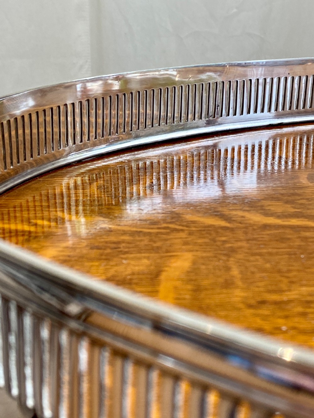 An oval 19th-century quarter-sawn oak gallery tray featuring a pierced silver-plated rim, central engraved shield plaque, and side carrying handles. View IX