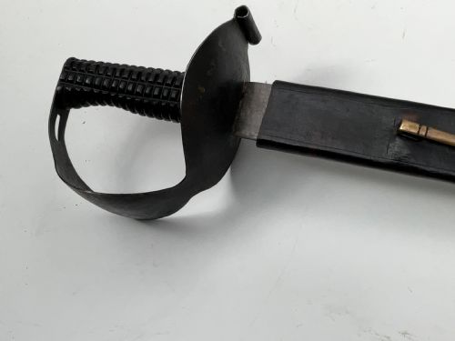 fig 1. A British 1804 pattern naval boarding cutlass featuring a black figure-eight iron handguard and a straight single-edged steel blade.