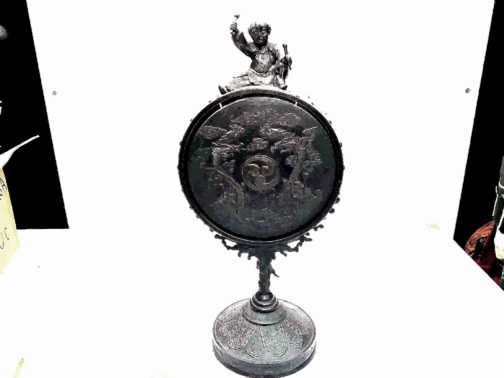 A Victorian dark bronze tabletop dinner gong featuring relief carving and a sculpted figure mounted atop a circular pedestal base.