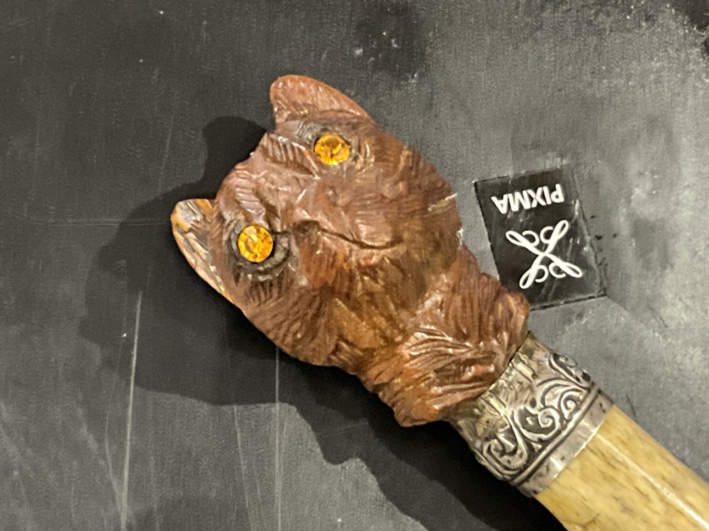 An antique wooden walking stick featuring a detailed carved animal head handle, metallic collars, and a dark polished shaft. View II