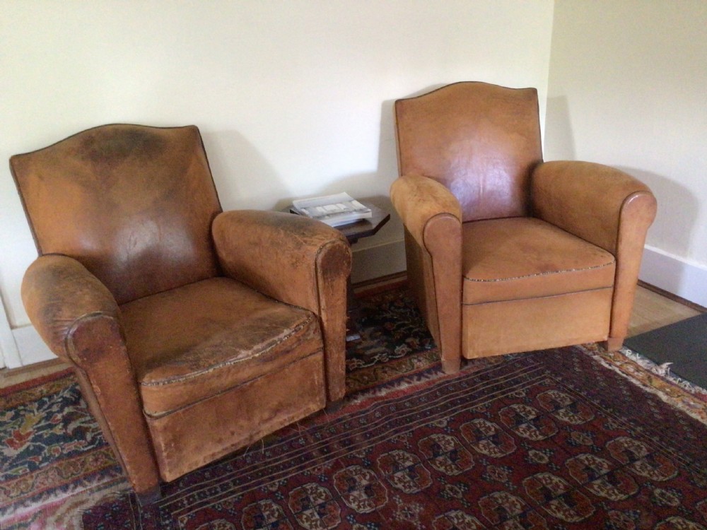 A pair of Art Deco tan leather club armchairs featuring rolled armrests, arched backrests, and aged surface patina. View II