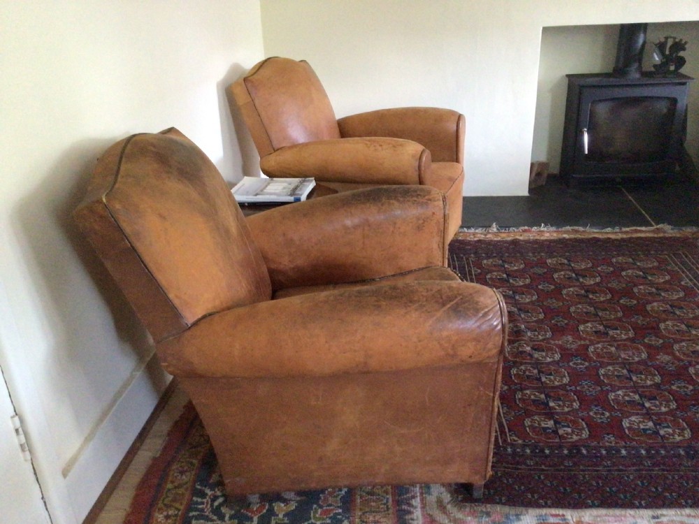 A pair of Art Deco tan leather club armchairs featuring rolled armrests, arched backrests, and aged surface patina. View III
