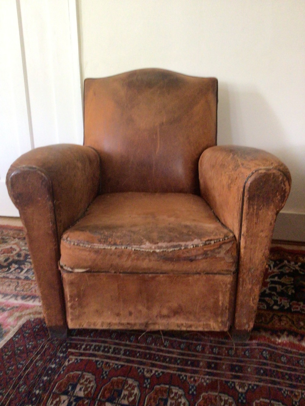 A pair of Art Deco tan leather club armchairs featuring rolled armrests, arched backrests, and aged surface patina. View IV