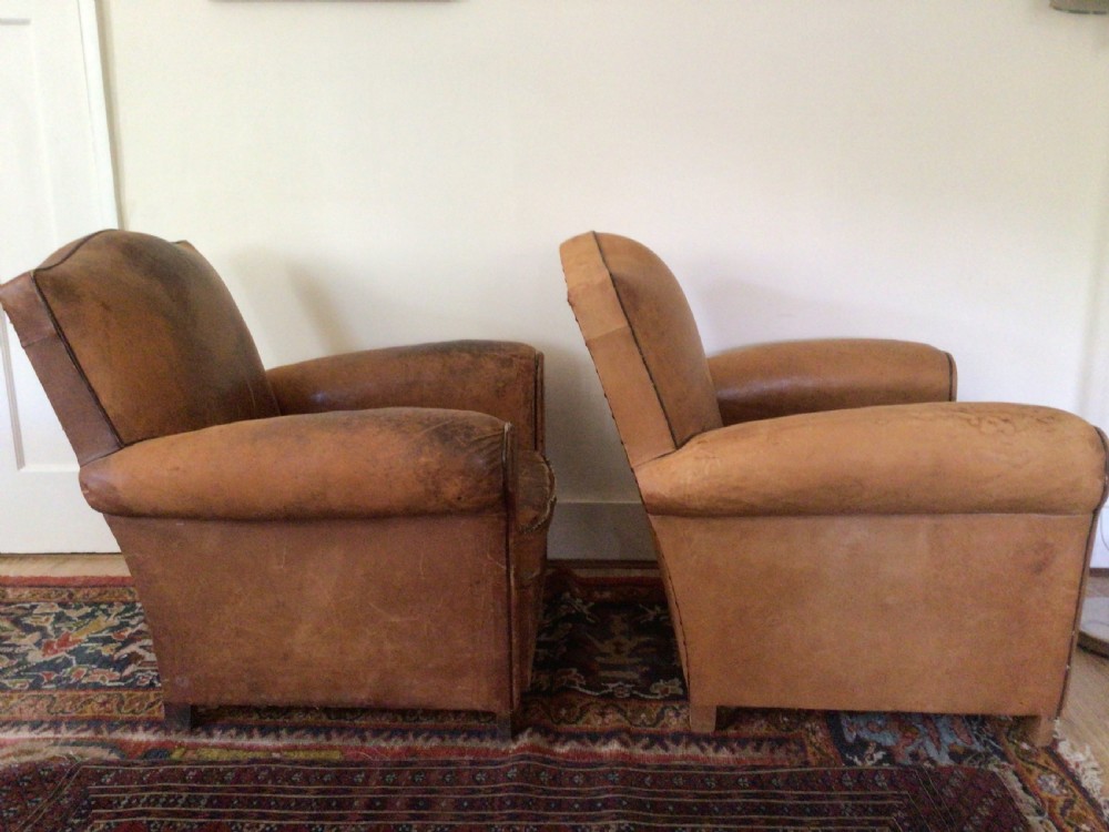 A pair of Art Deco tan leather club armchairs featuring rolled armrests, arched backrests, and aged surface patina. View V