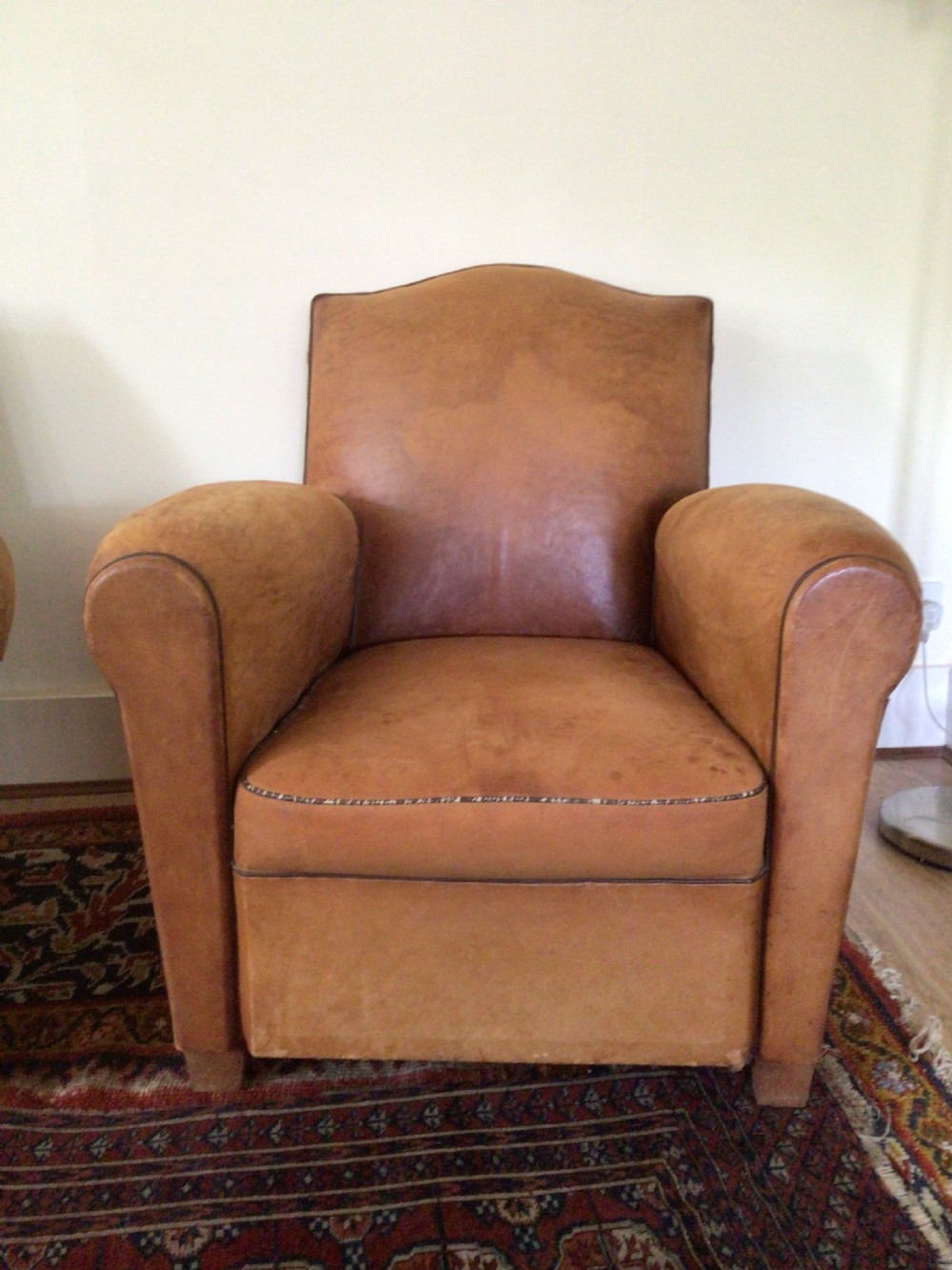 A pair of Art Deco tan leather club armchairs featuring rolled armrests, arched backrests, and aged surface patina. View VI