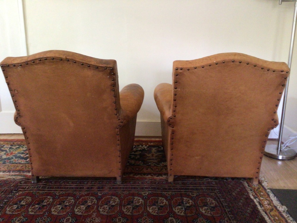 A pair of Art Deco tan leather club armchairs featuring rolled armrests, arched backrests, and aged surface patina. View VII