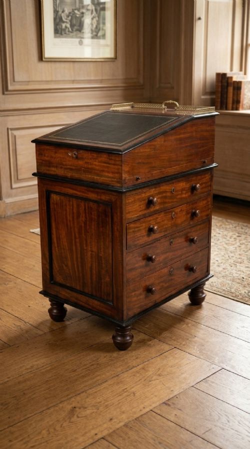 fig 1. A Regency mahogany Davenport desk featuring an inset leather sloped writing surface, ebonised borders, side drawers with turned wooden knobs, and a brass gallery top.