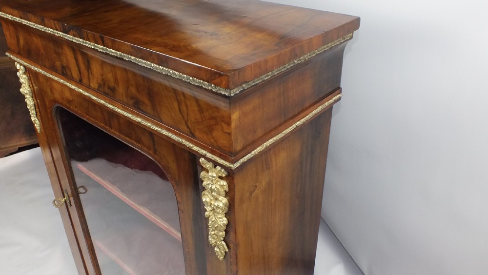 Mid-Victorian figured walnut pier cabinet featuring tulipwood banding, ormolu mounts, and a single glazed door showing velvet-lined shelves. View II
