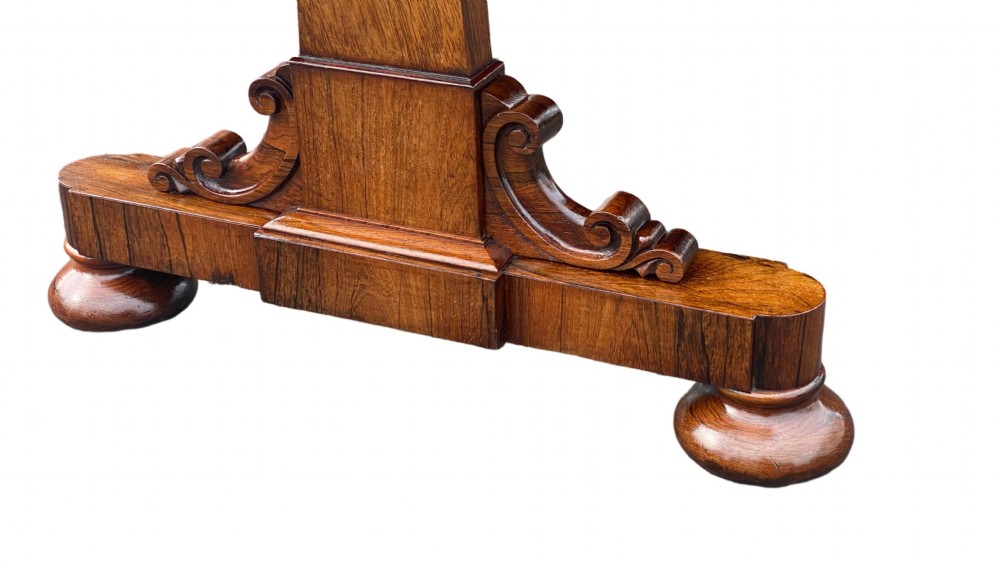 A late Regency rosewood library table featuring frieze drawers with brass handles on trestle end supports. View IV