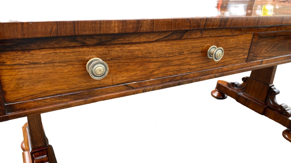 A late Regency rosewood library table featuring frieze drawers with brass handles on trestle end supports. View III