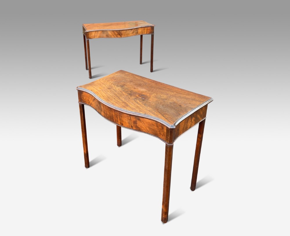 A pair of George III mahogany side tables featuring serpentine fronts and straight square legs.