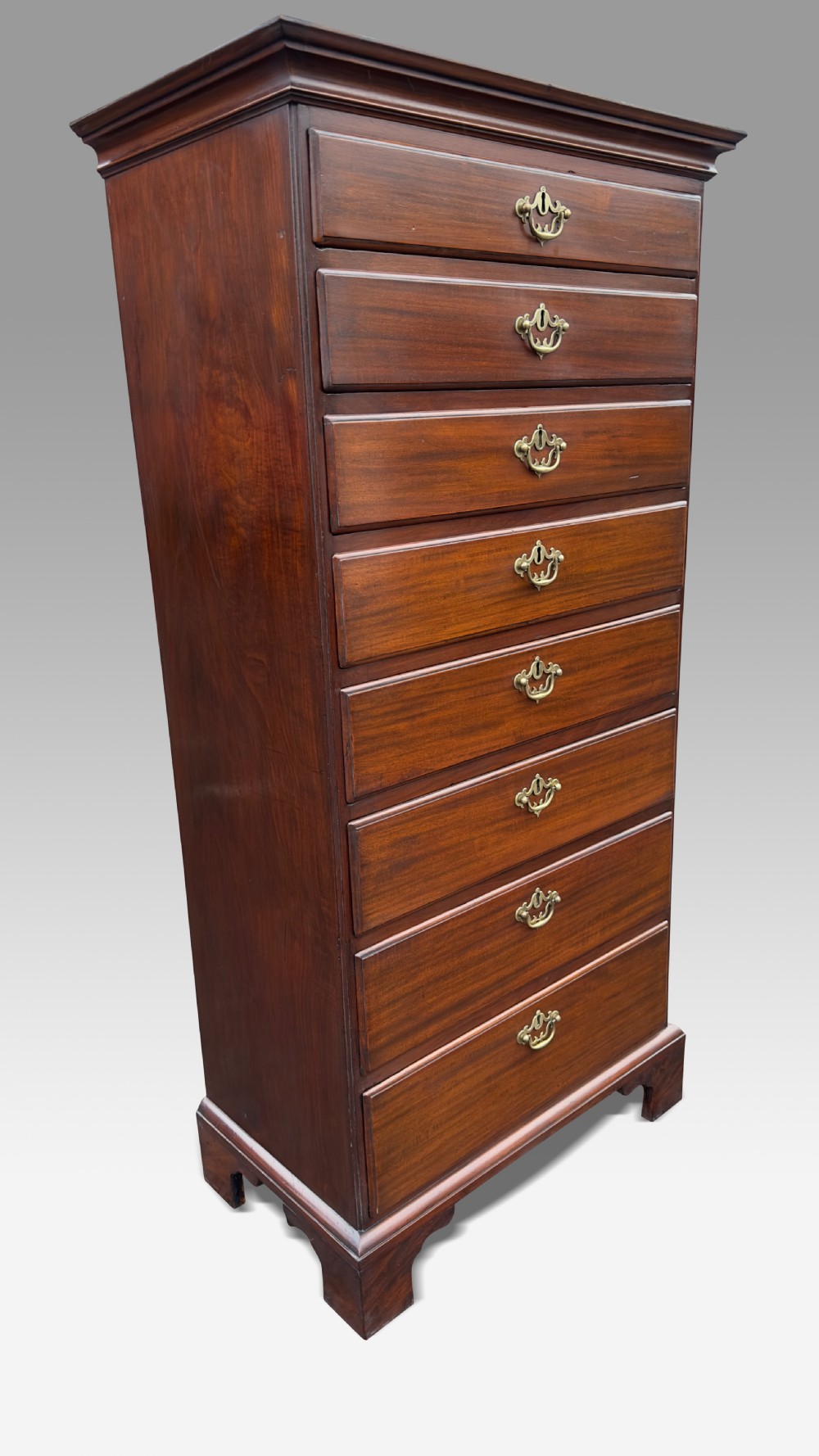 A mid-eighteenth-century Irish mahogany tallboy chest featuring eight graduated drawers with brass swan-neck handles and bracket feet.